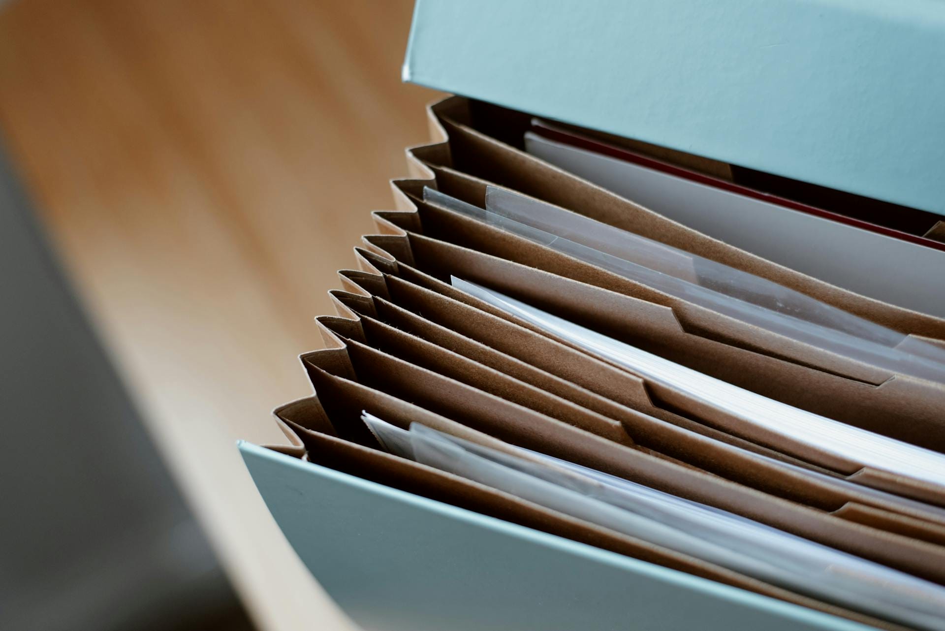 A partially open accordion file with brown dividers and visible documents inside.