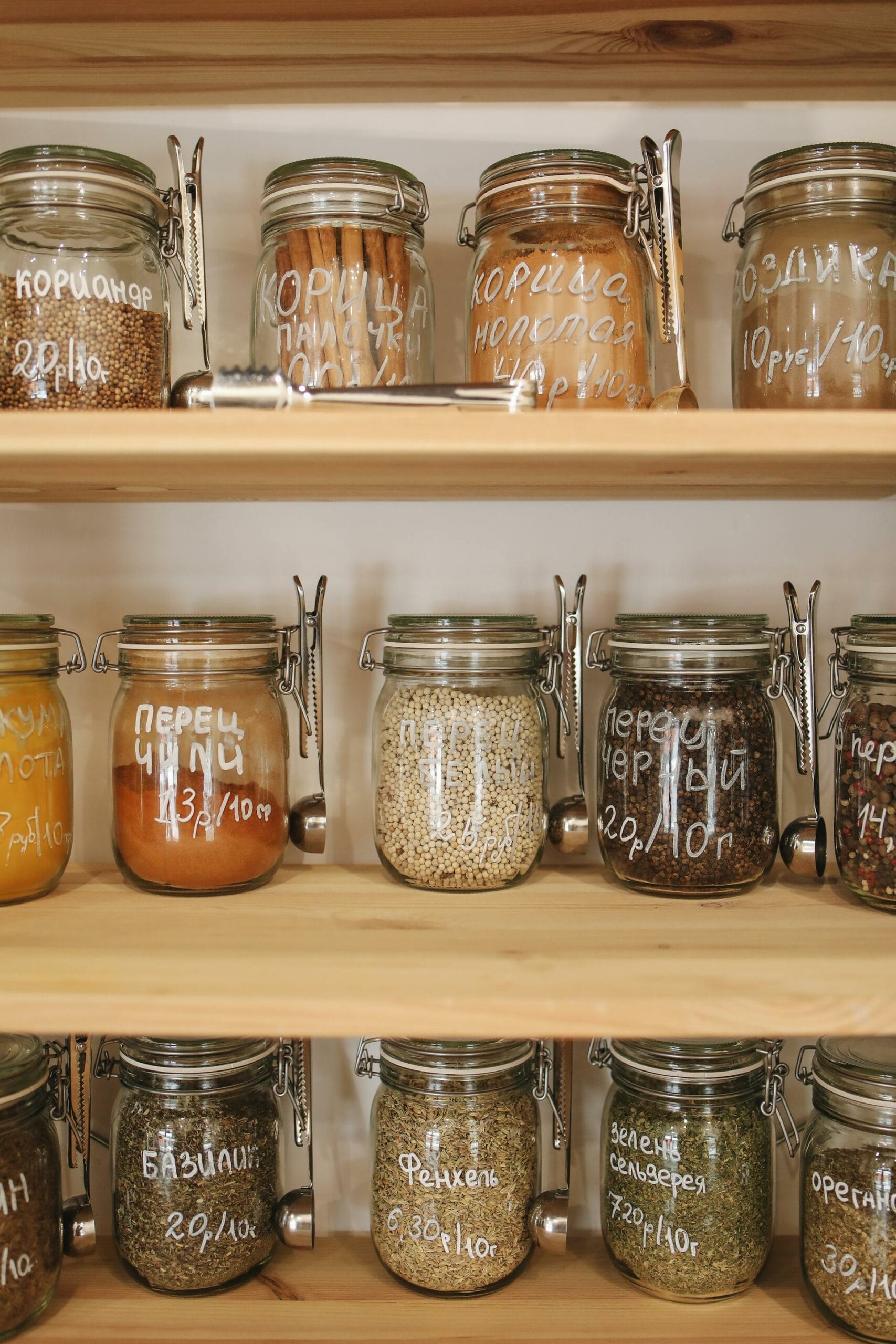 Jars of spices and herbs labeled in Cyrillic script are neatly arranged on wooden shelves.