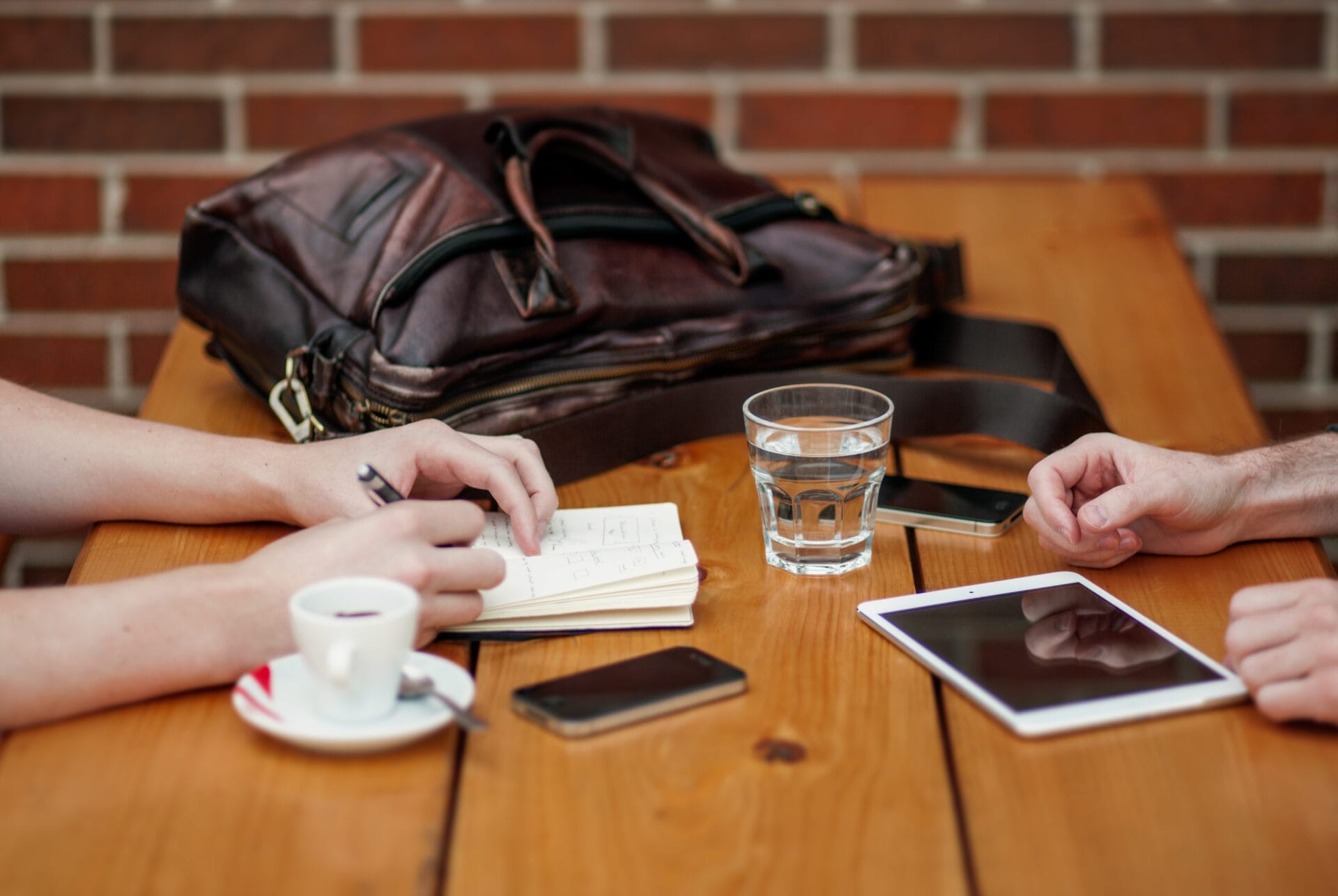 Man And Woman Having Business Meeting With Bag Drinks And Technology