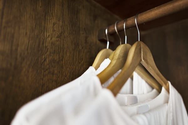 White Clothes Hanging In Wood Closet