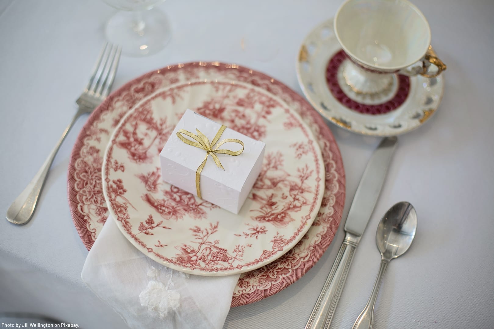 beautiful dishes with a red pattern and high quality silverware set at a table as an example of a life collection of dishes