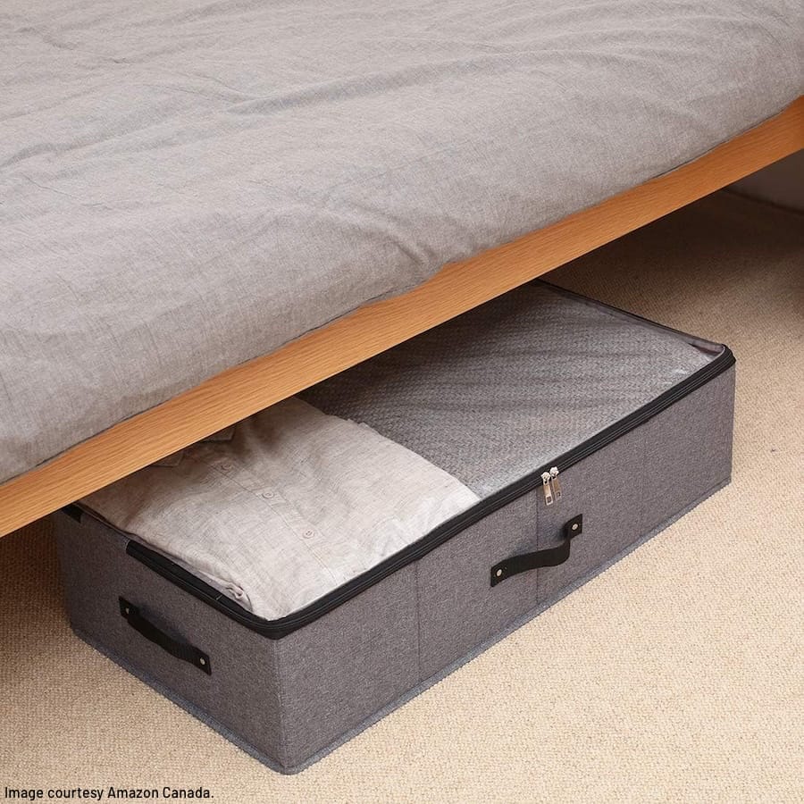 Collapsible storage box filled with linens half under a bed