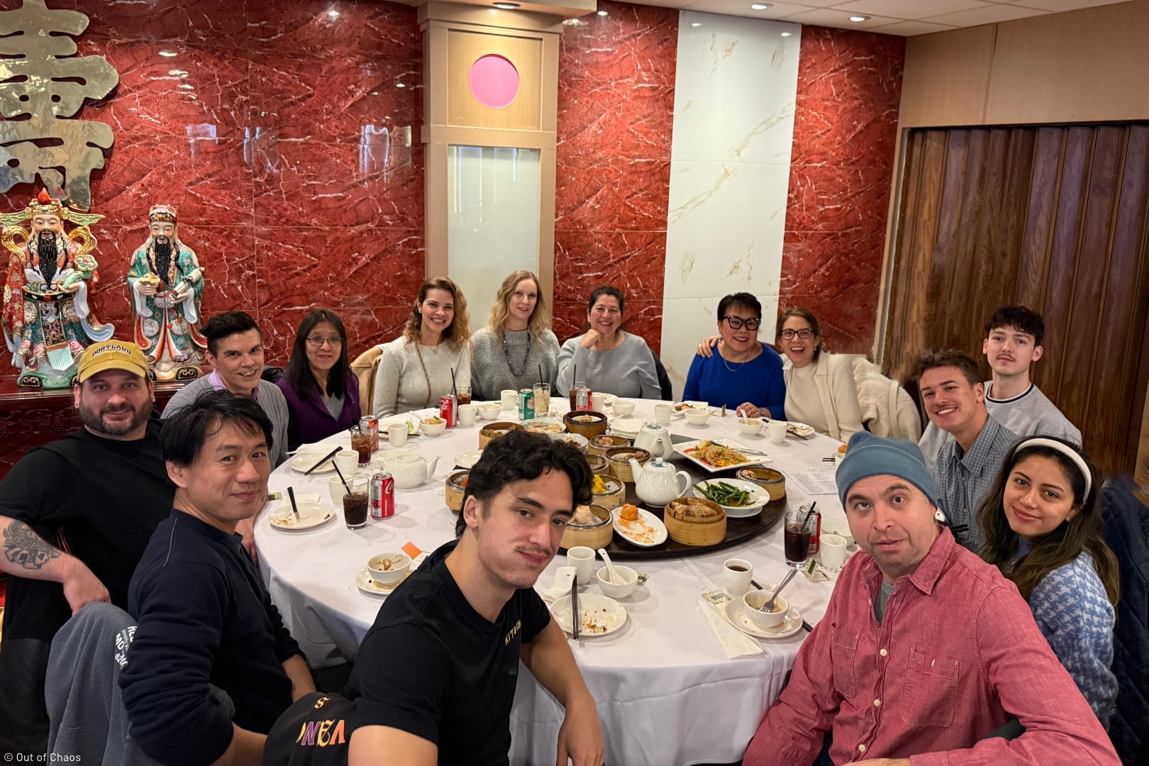 The Out of Chaos team sitting around a large table enjoying Dim Sum during a modern office holiday party